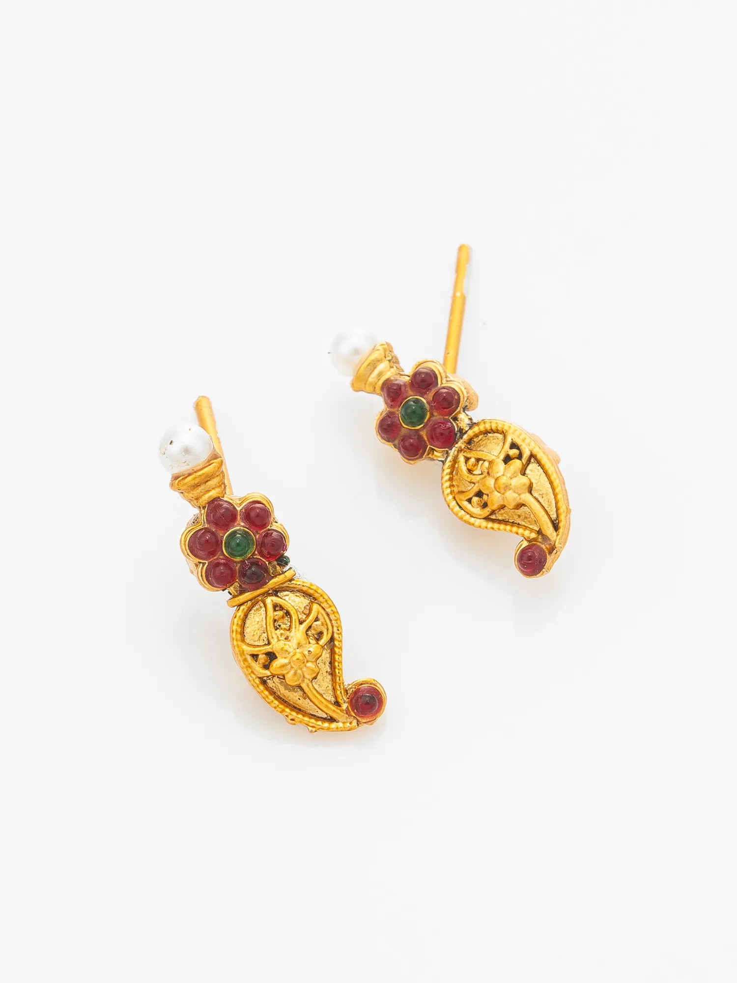 A pair of gold-plated traditional Indian earrings featuring paisley motifs, red enamel floral accents, green stone centers, and white pearl studs, displayed on a clean white background.