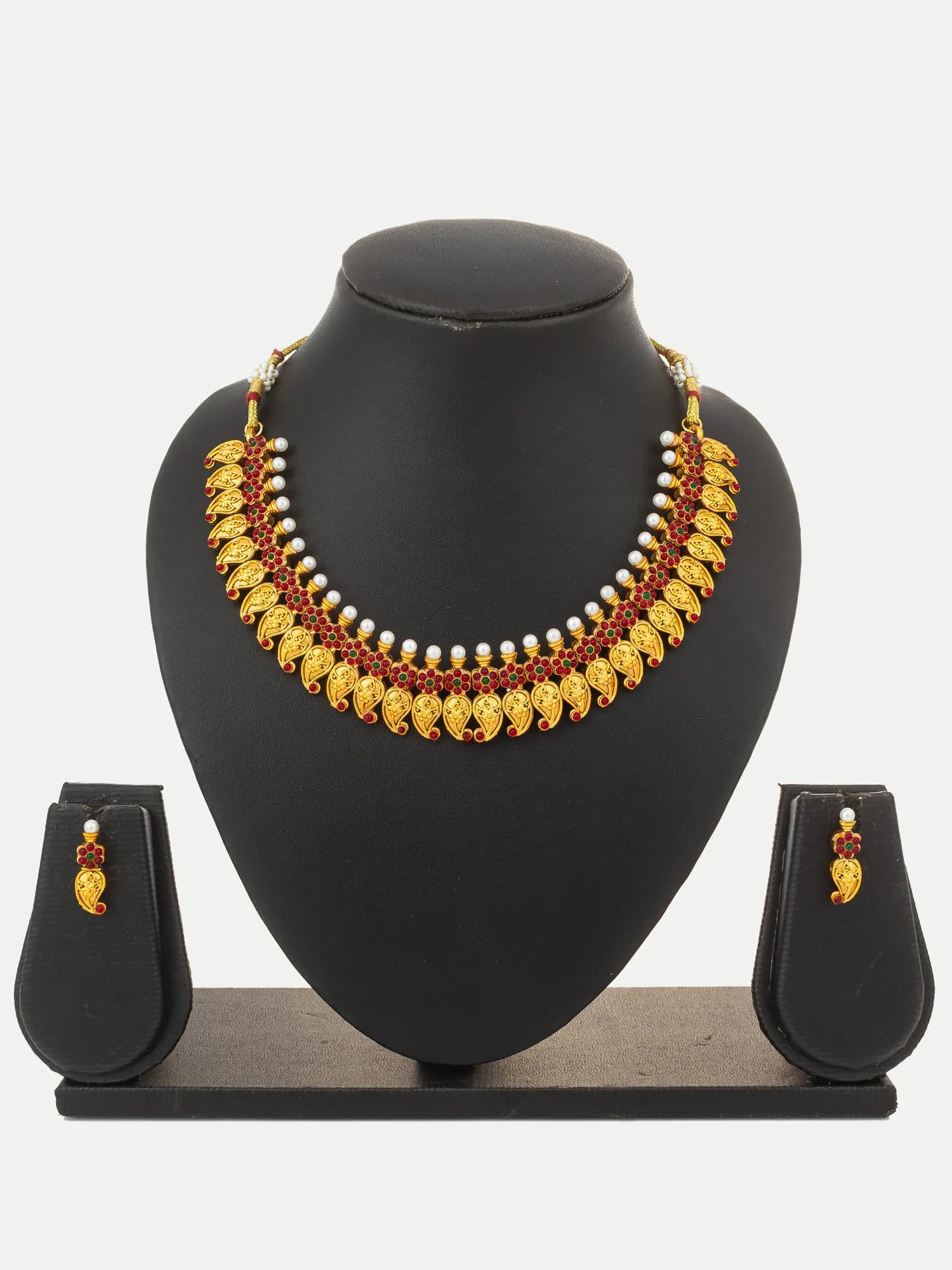 Gold and red jewelry set displayed on a black mannequin bust, featuring a statement necklace with gold leaf-like elements, white pearl-like beads, and matching drop earrings on a black stand.