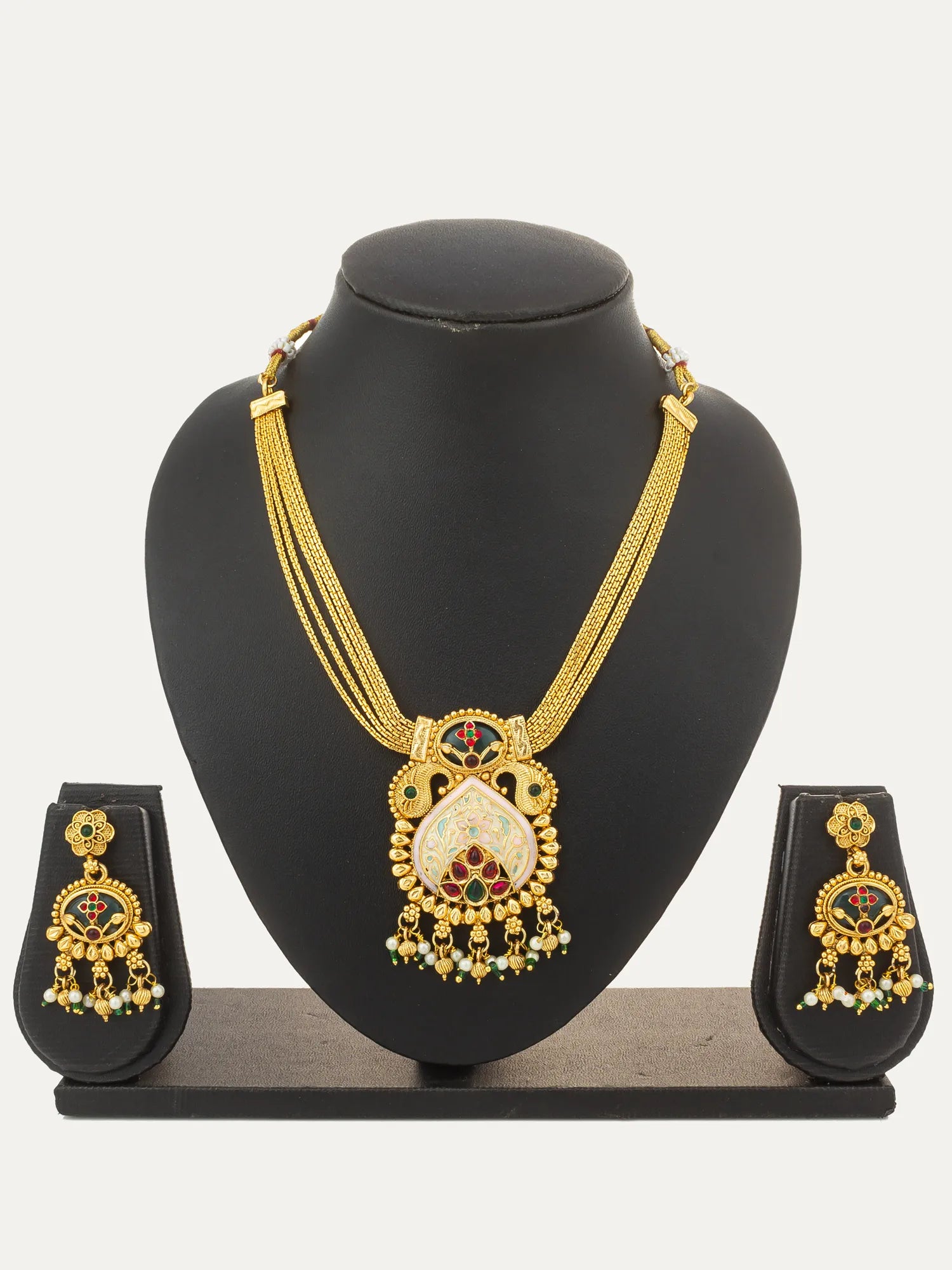 Gold-toned traditional Indian jewelry set featuring a necklace, earrings, and a matching ring displayed on a black jewelry bust against a light gray background.