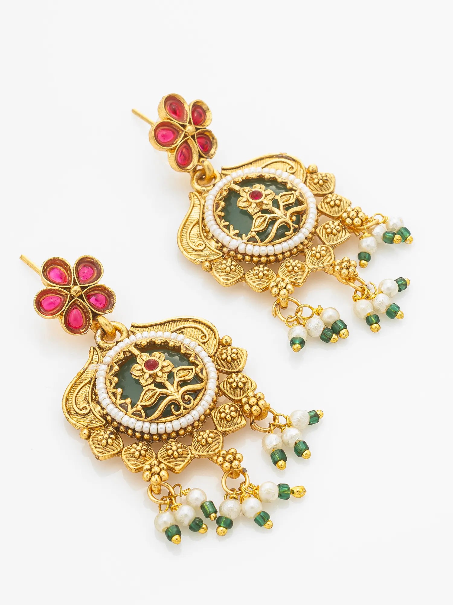 A pair of ornate gold-toned Indian jhumka earrings with green enamel inlays, white faux pearl borders, and dangling green and white bead clusters, shown on a plain white background.