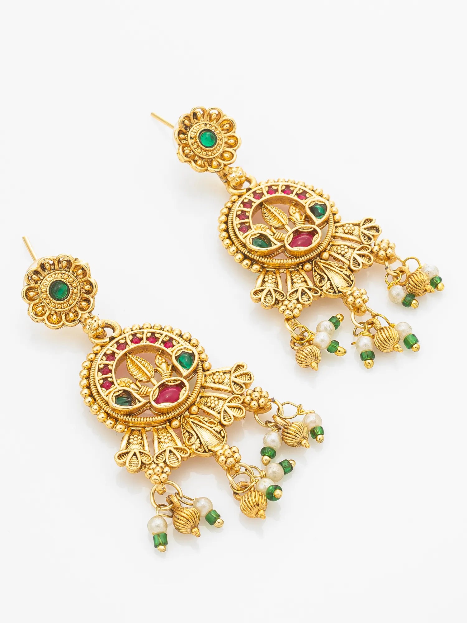 A pair of ornate gold-toned traditional Indian jhumka earrings with green and red enamel details, small white bead drops, and dangling gold elements, shown on a plain white background.