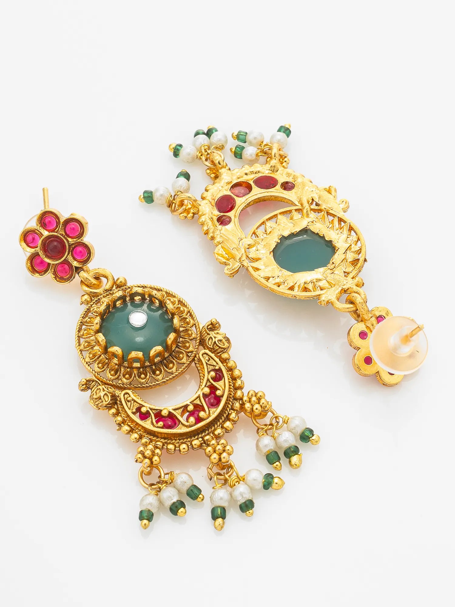 A pair of ornate gold-toned traditional Indian earrings decorated with green and red stones and white pearl-like beads, displayed on a clean white background.