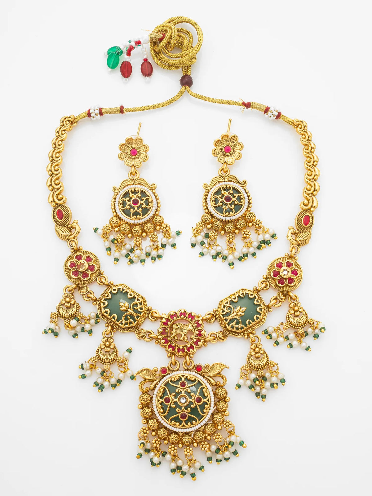 Gold-plated traditional Indian jewelry set including a statement necklace and matching earrings, decorated with green enamel, red stone accents, and dangling green bead chains, displayed on a clean white background.