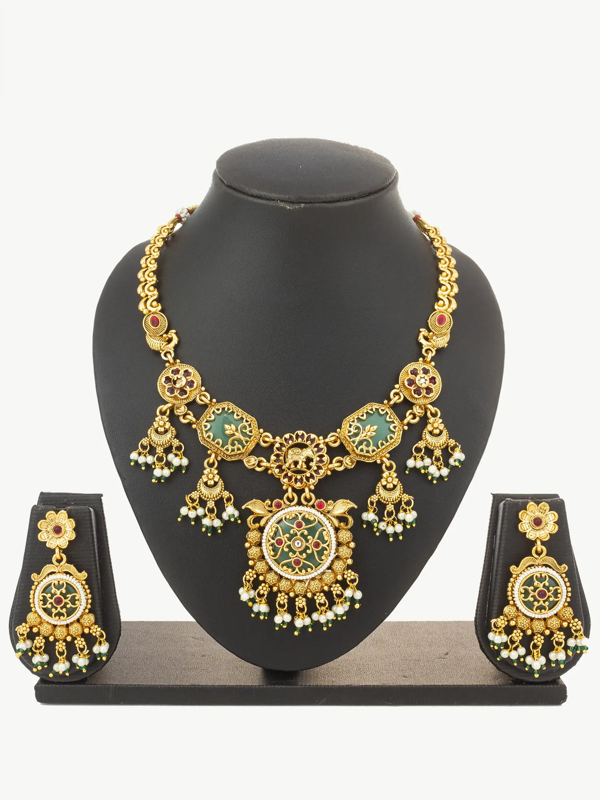 Gold-toned traditional jewelry set displayed on a black mannequin bust, including a statement necklace with green and red enamel details, matching drop earrings, and a small pendant on a black stand against a light gray background.
