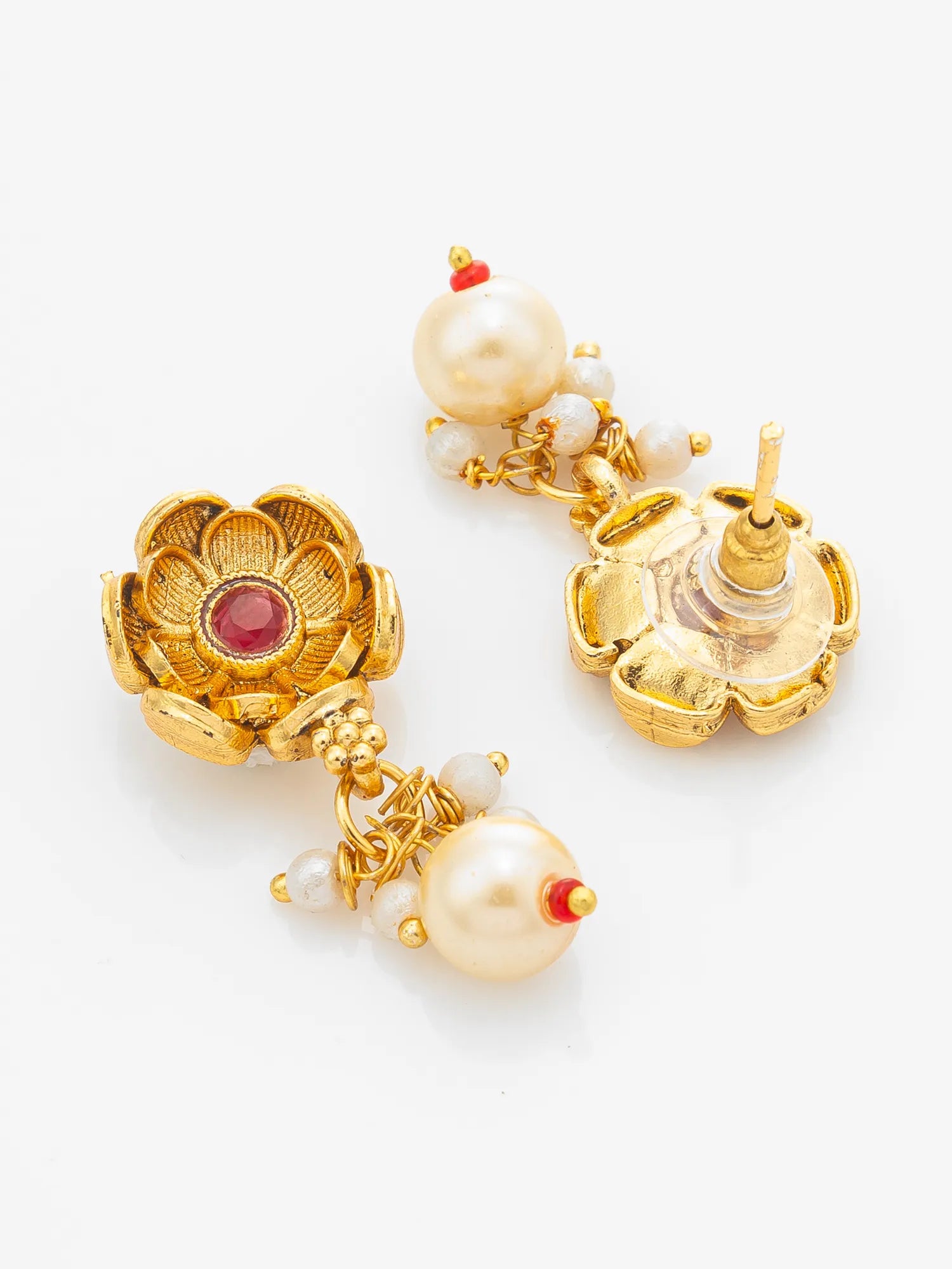 A pair of gold-plated traditional Indian earrings featuring lotus-shaped floral motifs, white pearls, and small red stone accents, displayed on a clean white background.