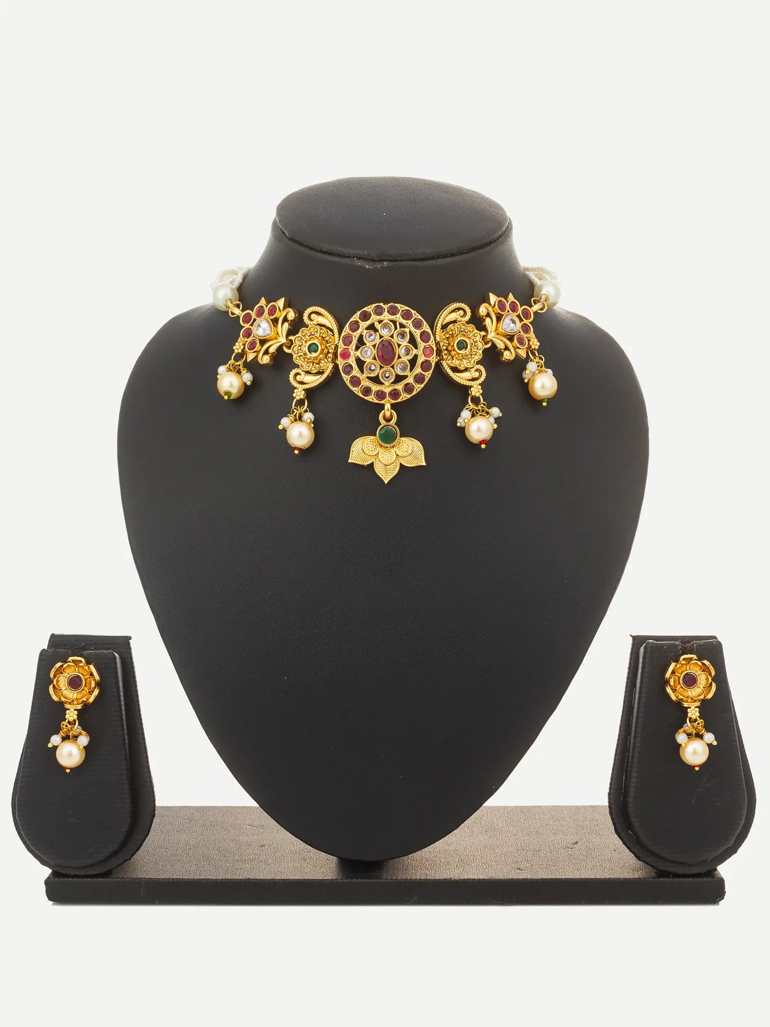 Gold-toned traditional jewelry set displayed on a black mannequin bust, including a choker necklace with floral motifs and dangling pearl-like beads, plus matching earrings on small display stands against a light gray background.
