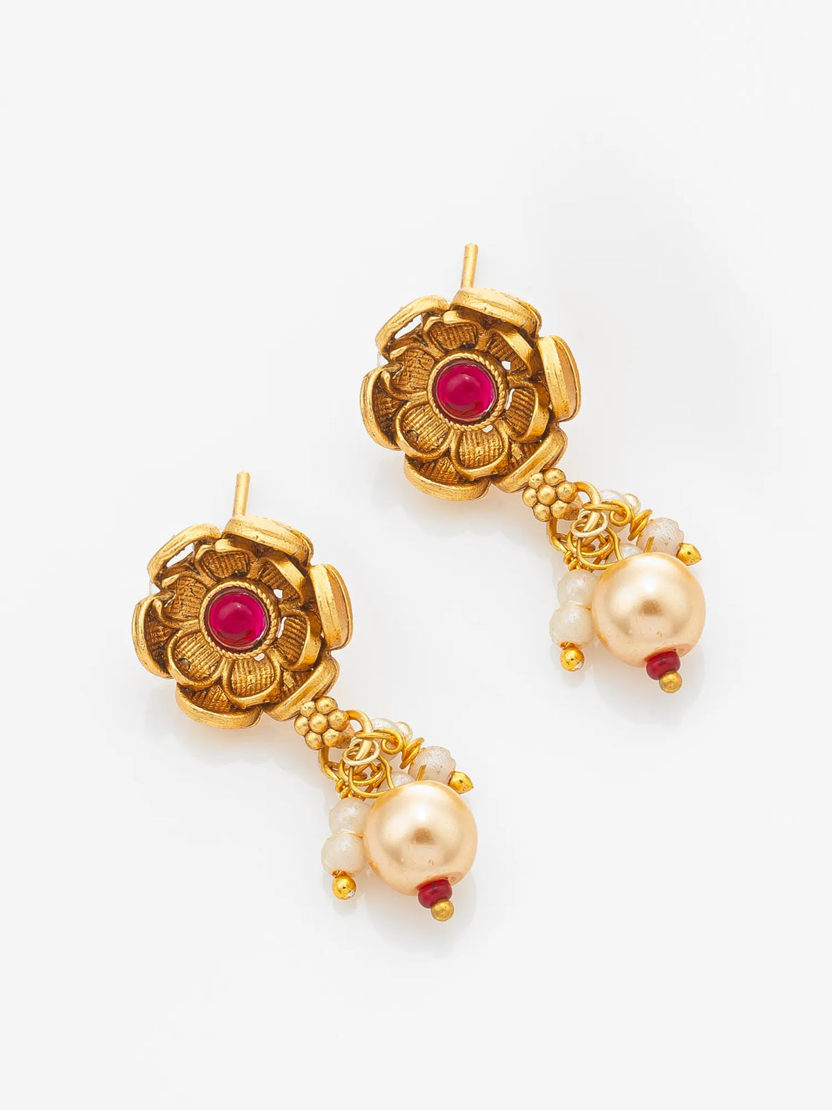 A pair of gold-toned traditional Indian dangle earrings featuring a floral motif with a central red stone and a dangling pearl bead accented with small white stones.