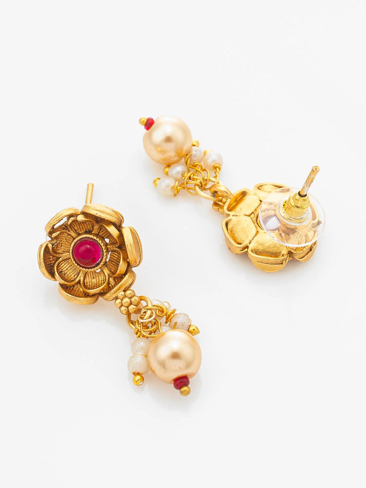 A pair of gold-toned traditional Indian earrings with white pearls, small red gemstone accents, and a central floral motif, displayed on a clean white background.