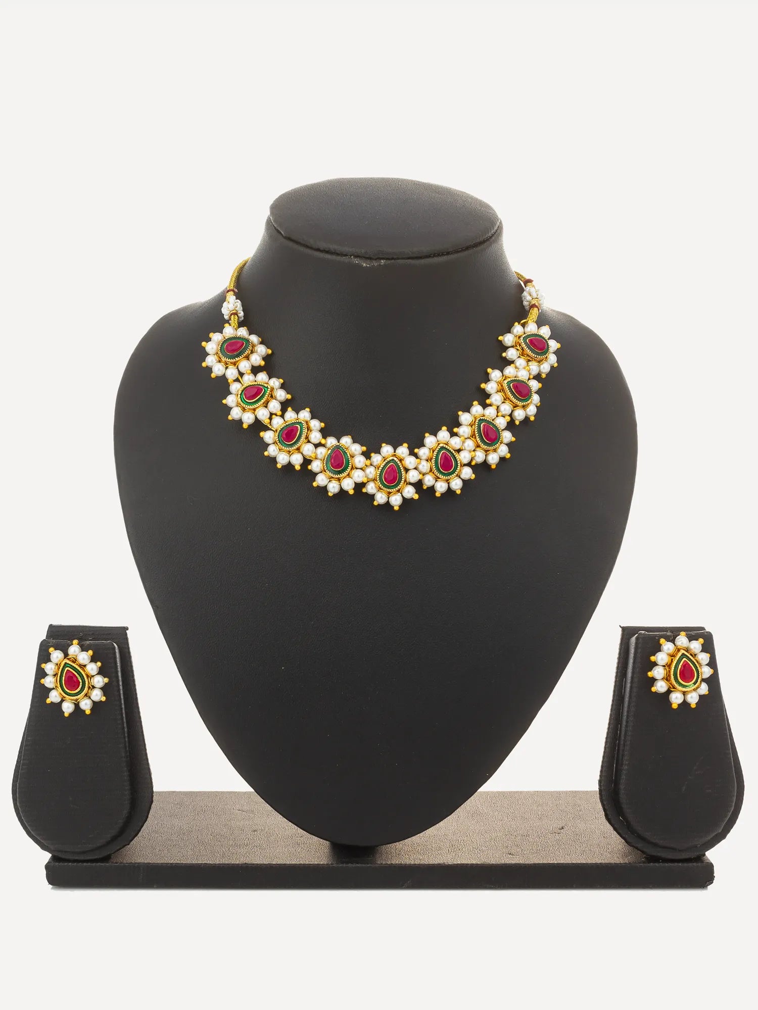 Gold-plated statement necklace and matching stud earrings set with red and white stones, displayed on a black jewelry bust stand against a white background.